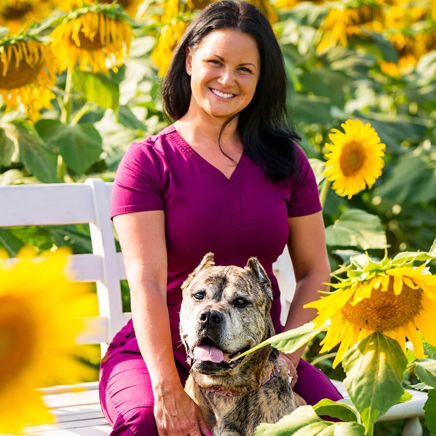 renee sitting by a dog in a sunflower field